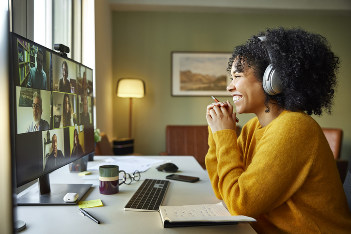 Businesswoman with headphones smiling during video conference. Multiracial male and female professionals are attending online meeting. They are discussing business strategy.